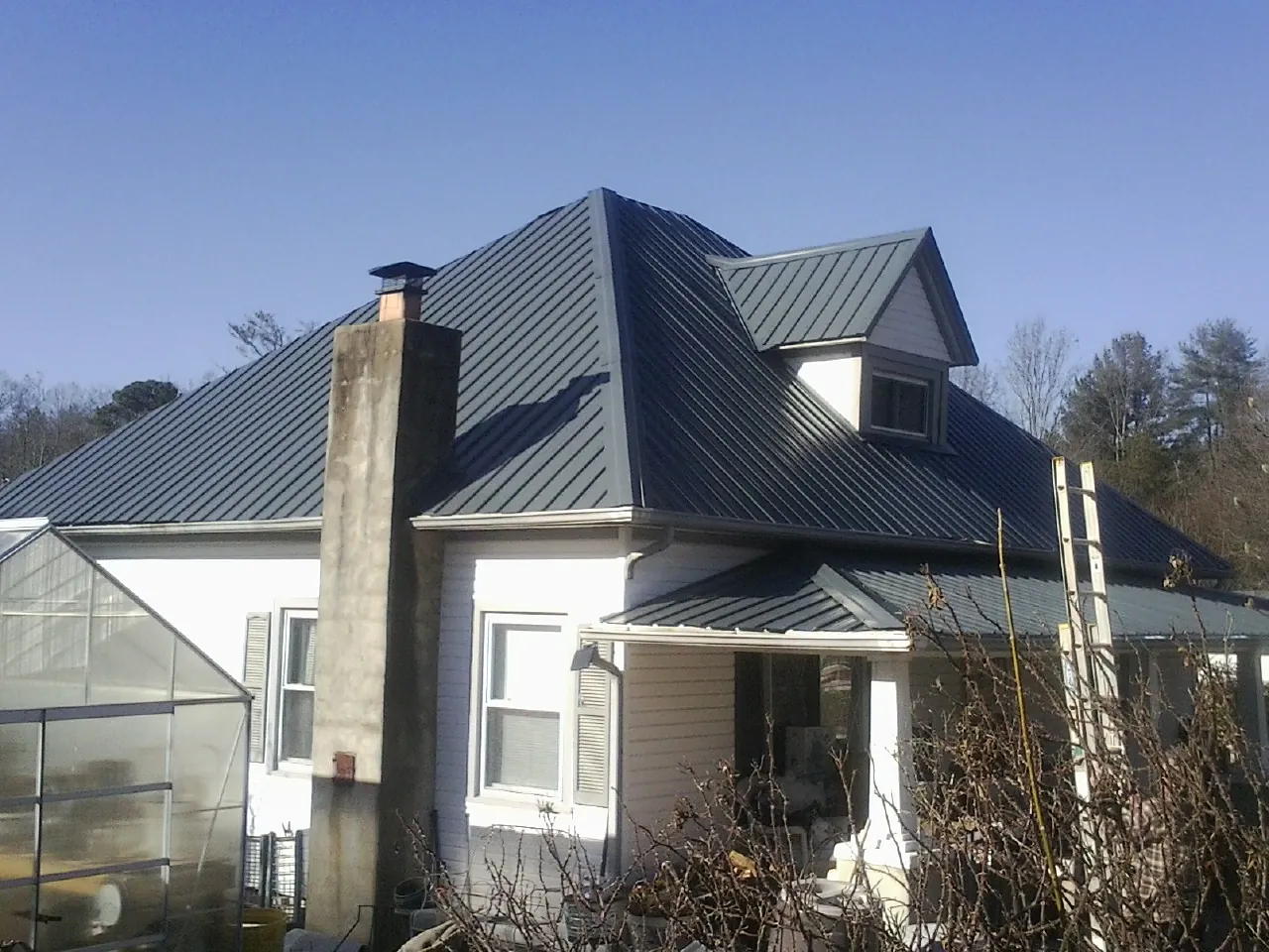 Dark blue standing seam metal roof on a white farmhouse with dormer — Slate & Tile Roof Repair by Roofing Brothers in Erving