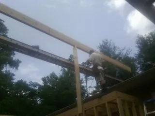 Carpenter setting a ridge beam over a new addition frame — Ice Dam Removal by Roofing Brothers in Erving