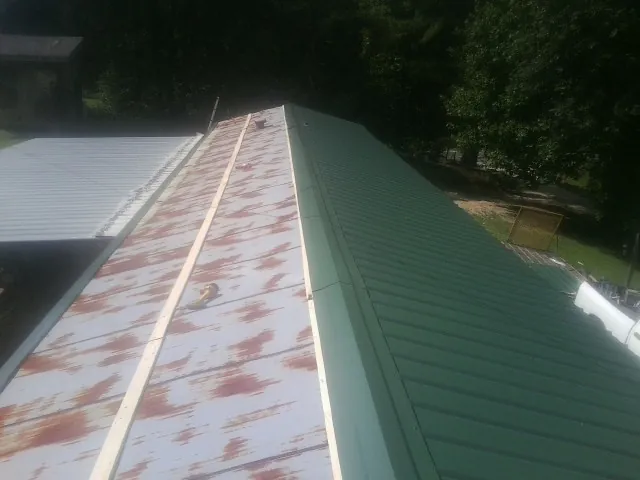 Old rusted panels beside newly installed green metal roofing — Wind Damage Roof Repair by Roofing Brothers in Erving