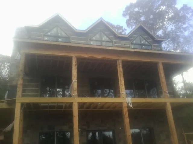 Dormers and porch framing on a large log home under construction — Roof Coating work by our crew in Erving