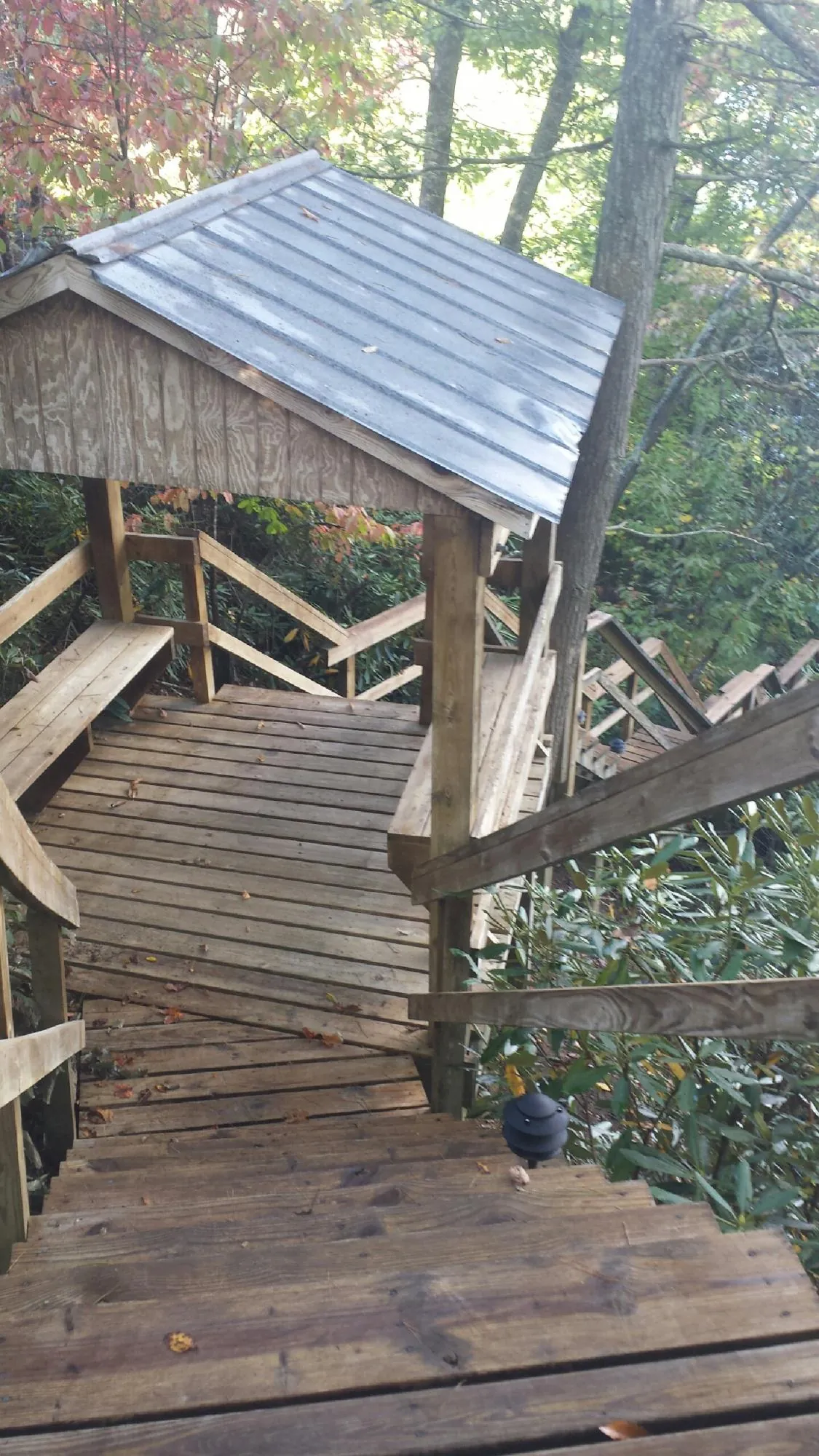 Metal roofed shelter over wooden steps on a wooded walkway — Skylight Repair & Installation work by our crew in Erving