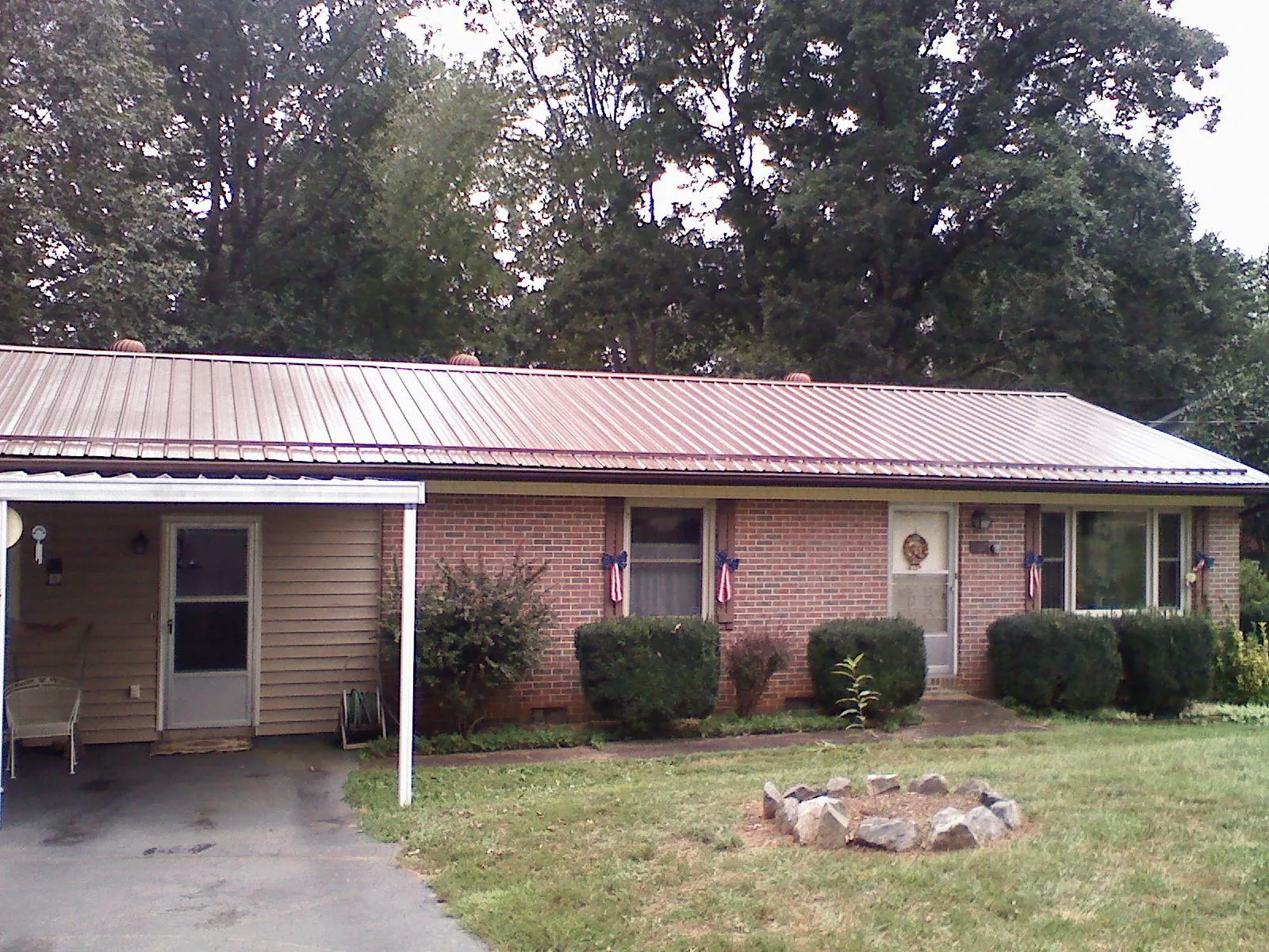 Bronze metal roof and carport on a brick ranch home — Roof Repair work by our crew in Erving